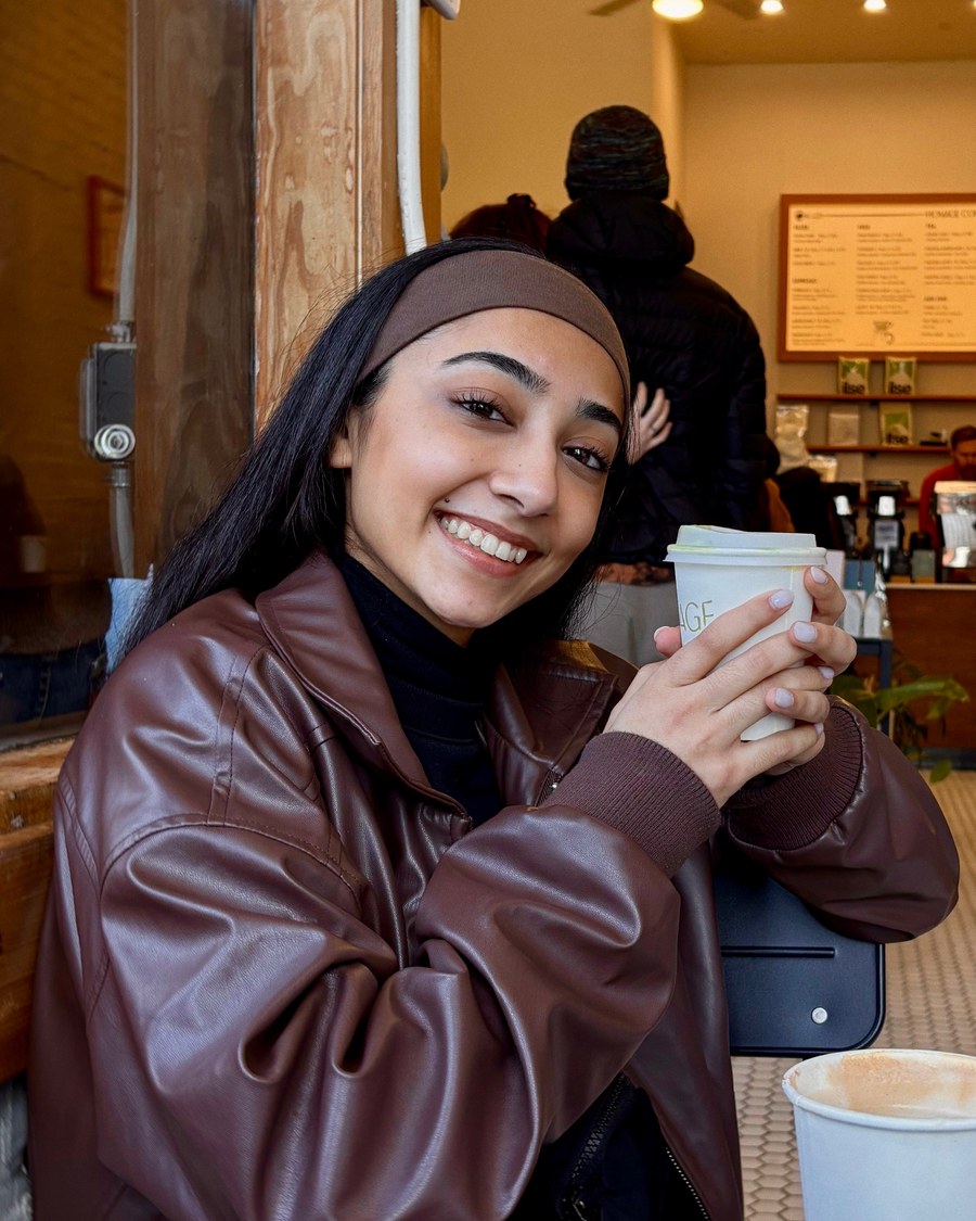 Leen Kaur sitting in a coffee shop holding a cup